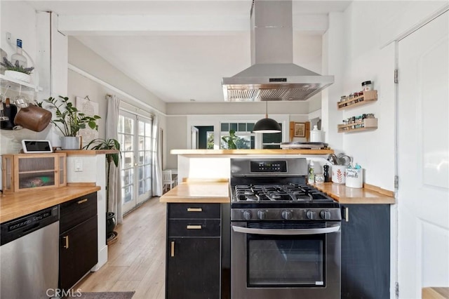 kitchen with light hardwood / wood-style floors, butcher block countertops, island exhaust hood, appliances with stainless steel finishes, and french doors