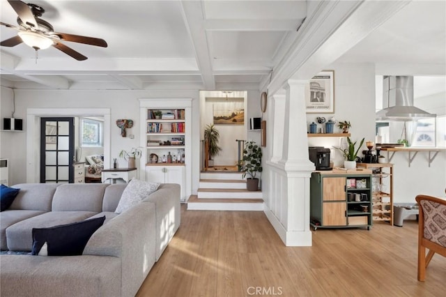 living room featuring ornate columns, coffered ceiling, ceiling fan, light hardwood / wood-style flooring, and beamed ceiling