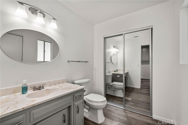 bathroom with toilet, vanity, and hardwood / wood-style flooring