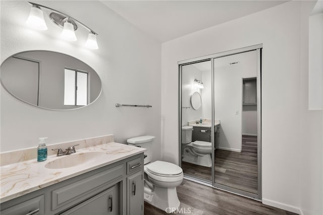 bathroom with vanity, wood finished floors, toilet, and baseboards