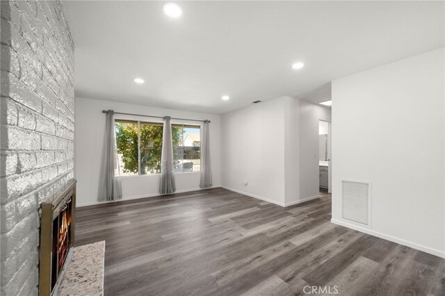 unfurnished living room with dark wood-type flooring and a fireplace