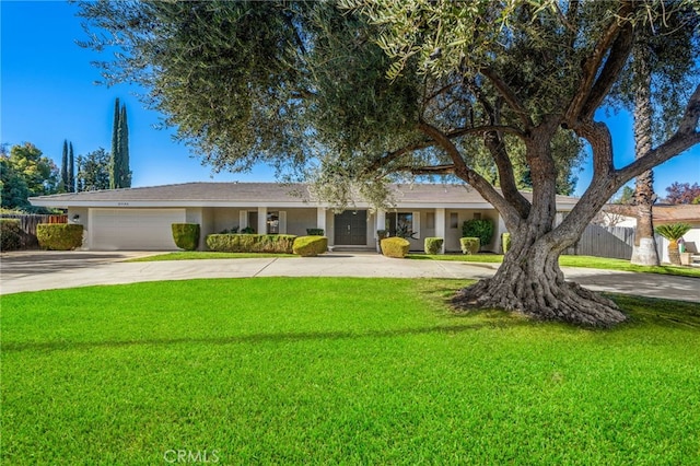 view of front of house featuring a garage, fence, concrete driveway, and a front yard