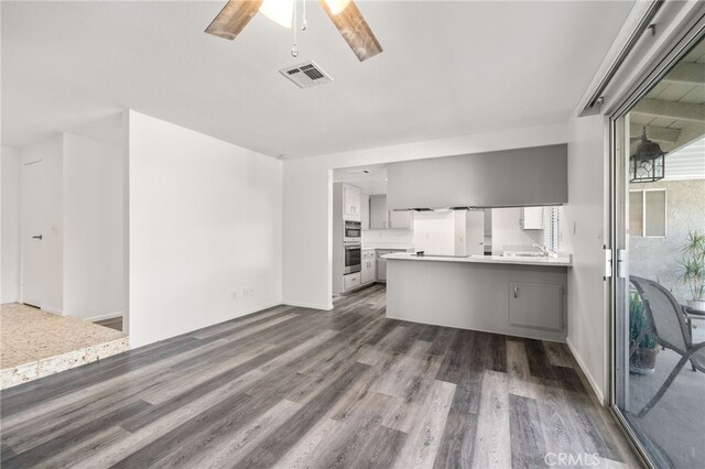 kitchen with ceiling fan, white cabinetry, dark hardwood / wood-style flooring, and kitchen peninsula