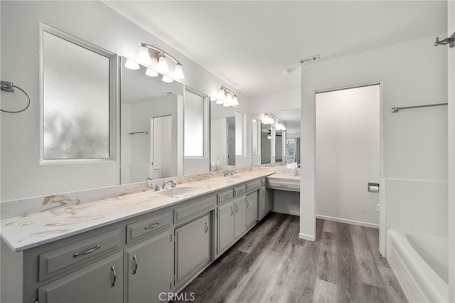 full bath with a tub to relax in, visible vents, vanity, and wood finished floors