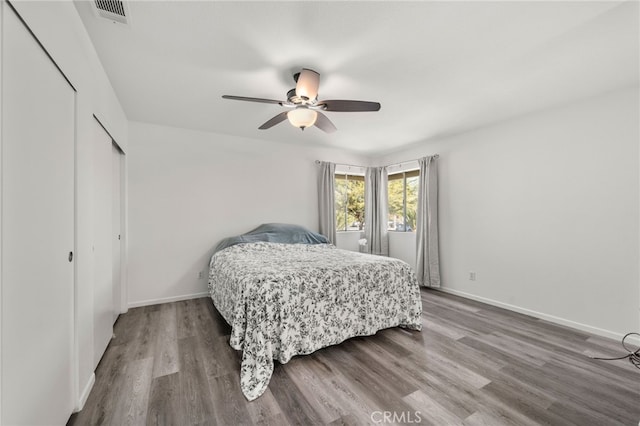 bedroom featuring baseboards, a closet, visible vents, and wood finished floors