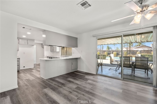 kitchen with a peninsula, light countertops, dark wood finished floors, and visible vents