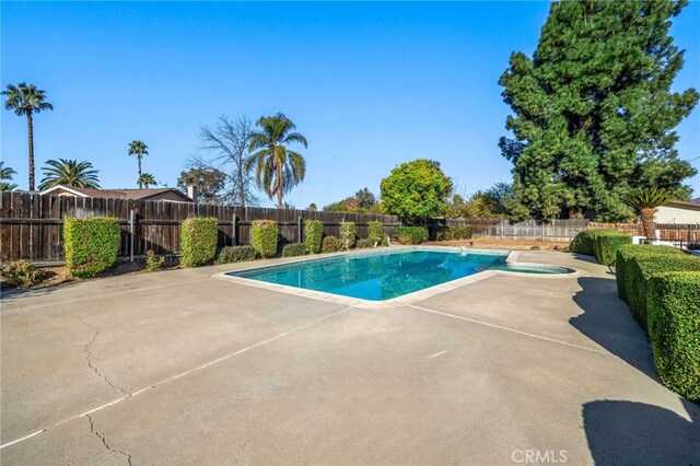 view of swimming pool featuring a hot tub and a patio