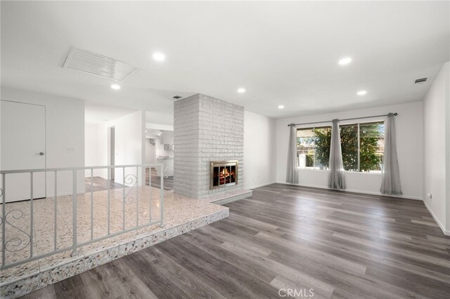 unfurnished living room featuring a brick fireplace and dark hardwood / wood-style flooring