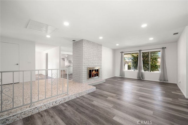 unfurnished living room with a fireplace, wood finished floors, visible vents, and recessed lighting