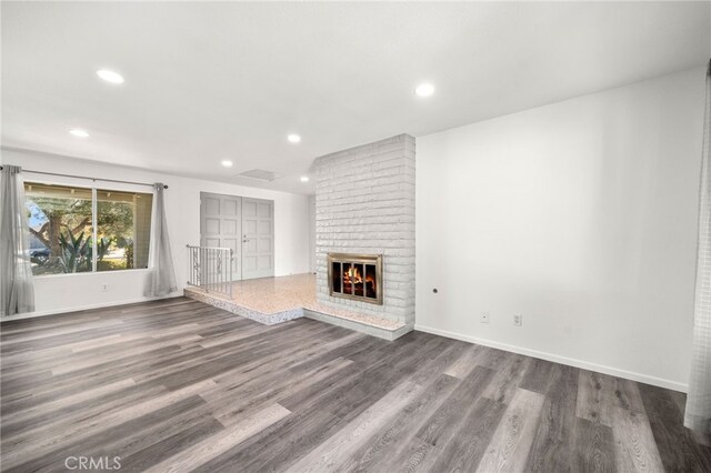 unfurnished living room with a brick fireplace and dark hardwood / wood-style floors