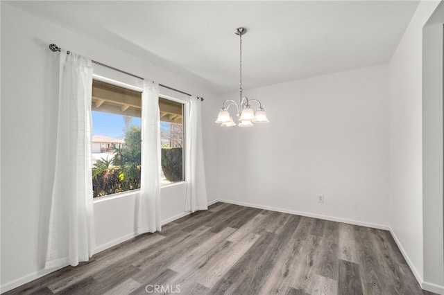 unfurnished dining area with a notable chandelier, baseboards, and wood finished floors