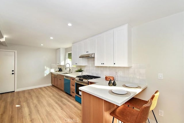 kitchen featuring white cabinetry, sink, stainless steel appliances, backsplash, and a breakfast bar area