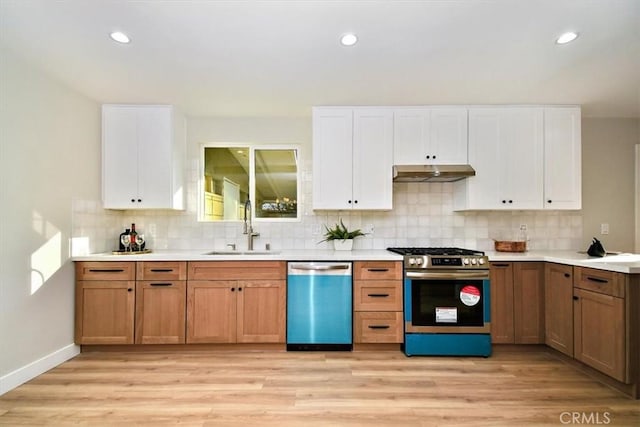 kitchen featuring white cabinetry, sink, light hardwood / wood-style floors, decorative backsplash, and appliances with stainless steel finishes