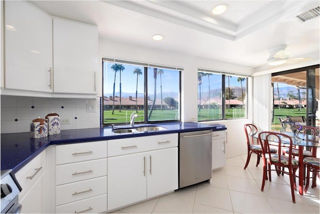 kitchen with tasteful backsplash, stove, stainless steel dishwasher, white cabinets, and sink