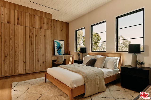 bedroom with light hardwood / wood-style floors and wooden walls