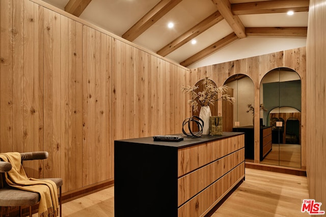 interior space with vaulted ceiling with beams, light hardwood / wood-style flooring, and wood walls