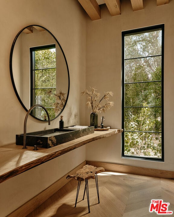 bathroom with parquet floors, beam ceiling, and sink