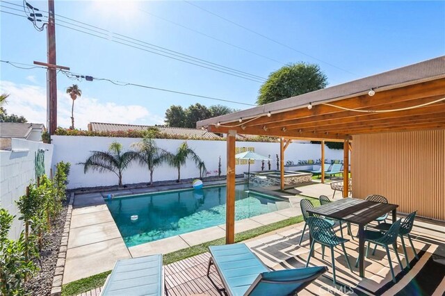 view of swimming pool with a patio, a fenced backyard, a pool with connected hot tub, and outdoor dining area