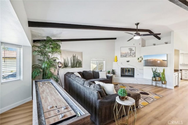 living room featuring light hardwood / wood-style flooring, vaulted ceiling with beams, a fireplace, and ceiling fan