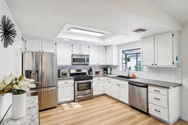 kitchen featuring tasteful backsplash, visible vents, a sink, light wood-type flooring, and stainless steel appliances