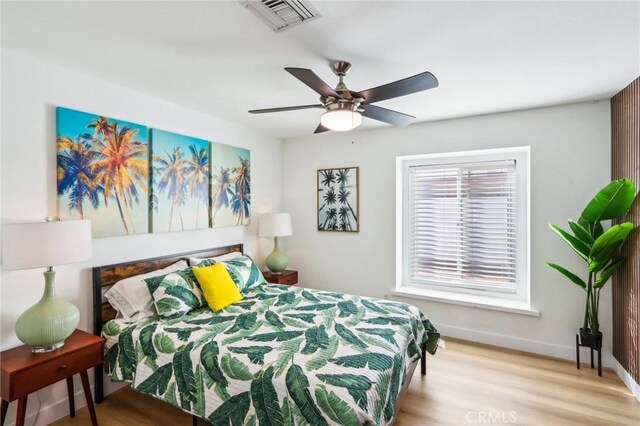 bedroom featuring wood finished floors, baseboards, a ceiling fan, and visible vents
