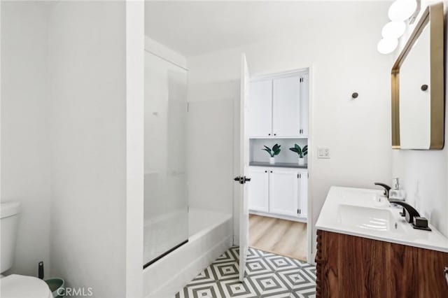 bathroom featuring vanity, a shower with shower door, and toilet