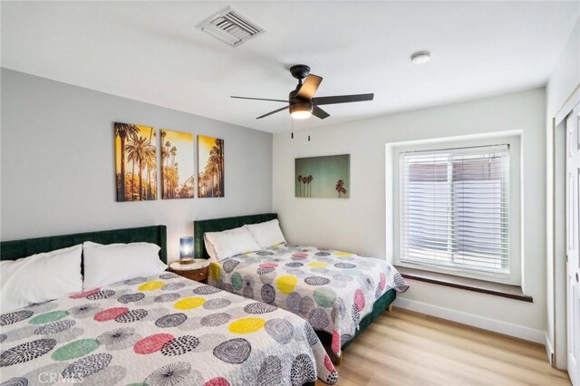 bedroom featuring visible vents, baseboards, a ceiling fan, and wood finished floors