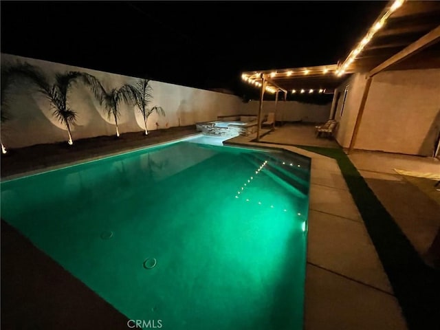 pool at twilight featuring an in ground hot tub and a patio area