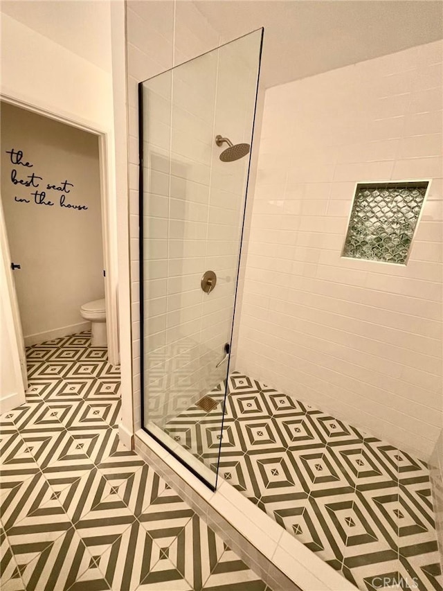 bathroom with a tile shower, tile patterned floors, and toilet