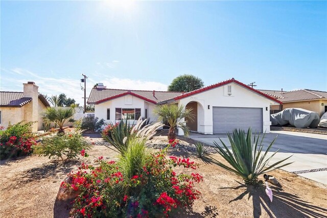 mediterranean / spanish-style home with a tile roof, stucco siding, a garage, and concrete driveway