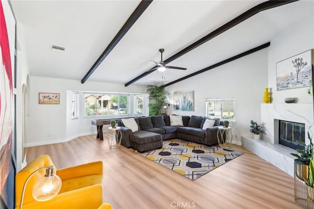 living room with hardwood / wood-style flooring, ceiling fan, a premium fireplace, and vaulted ceiling with beams