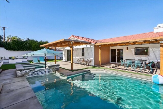 view of pool with a patio area, a pool with connected hot tub, and fence