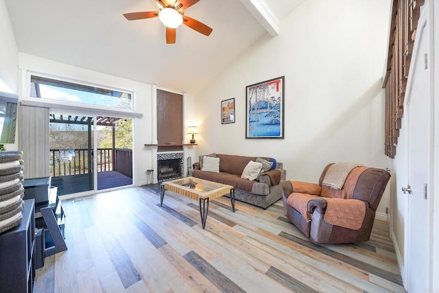 living room featuring ceiling fan, a tile fireplace, high vaulted ceiling, and light wood-type flooring