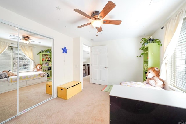 bedroom featuring ceiling fan, light colored carpet, and a closet