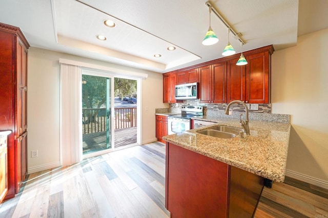 kitchen featuring stainless steel appliances, a raised ceiling, hanging light fixtures, and sink