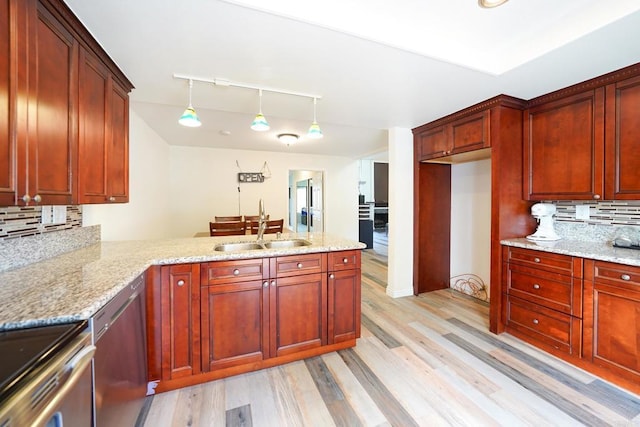 kitchen featuring dishwasher, kitchen peninsula, sink, hanging light fixtures, and light stone counters