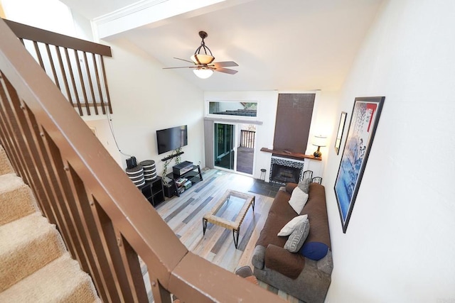 living room featuring ceiling fan, light hardwood / wood-style floors, a tile fireplace, and lofted ceiling