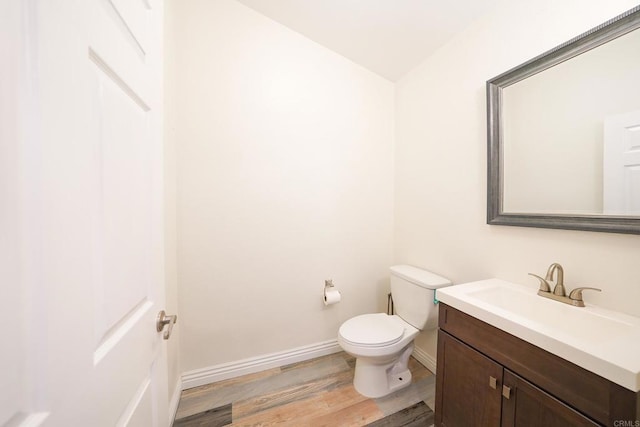 bathroom with toilet, wood-type flooring, and vanity