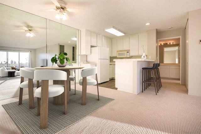 carpeted dining room featuring a textured ceiling and ceiling fan