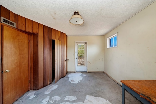 unfurnished room with wood walls and a textured ceiling