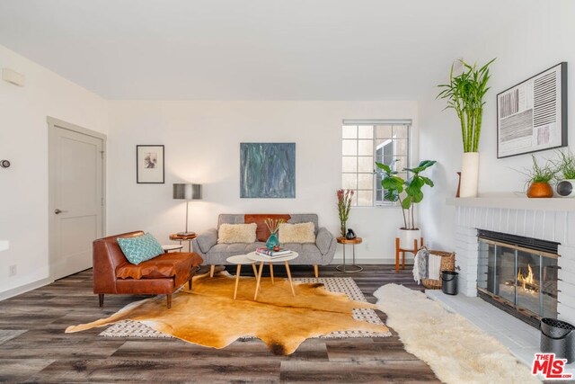 living room featuring wood-type flooring and a brick fireplace