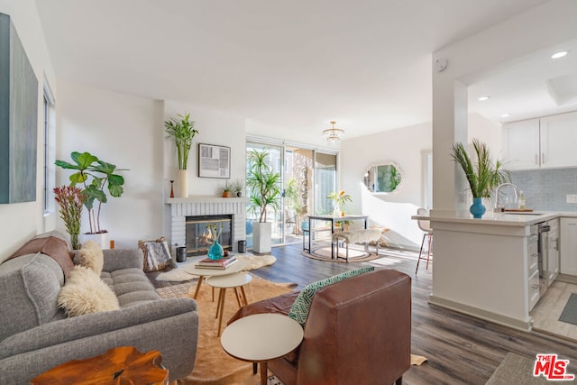 living room featuring sink, a brick fireplace, and dark hardwood / wood-style floors