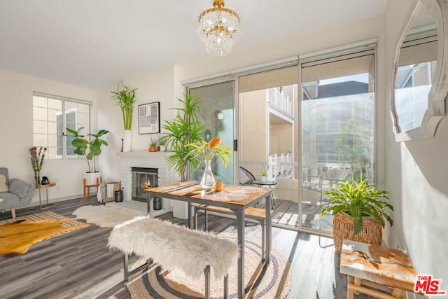 dining room with a brick fireplace, a healthy amount of sunlight, and wood-type flooring