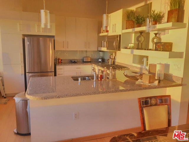 kitchen with stainless steel refrigerator, white cabinetry, kitchen peninsula, and pendant lighting