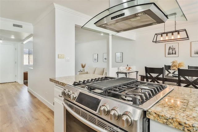 kitchen featuring hanging light fixtures, white cabinets, stainless steel gas stove, and island exhaust hood