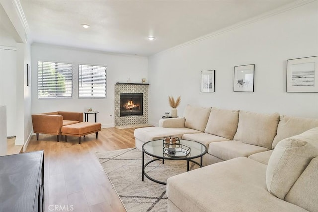 living room with a fireplace, ornamental molding, and light hardwood / wood-style flooring