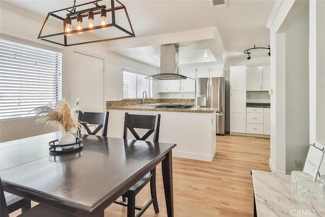 dining area featuring light hardwood / wood-style floors, a raised ceiling, a notable chandelier, ornamental molding, and sink