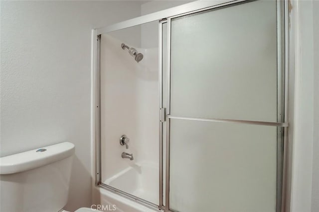 bathroom with toilet and shower / bath combination with glass door