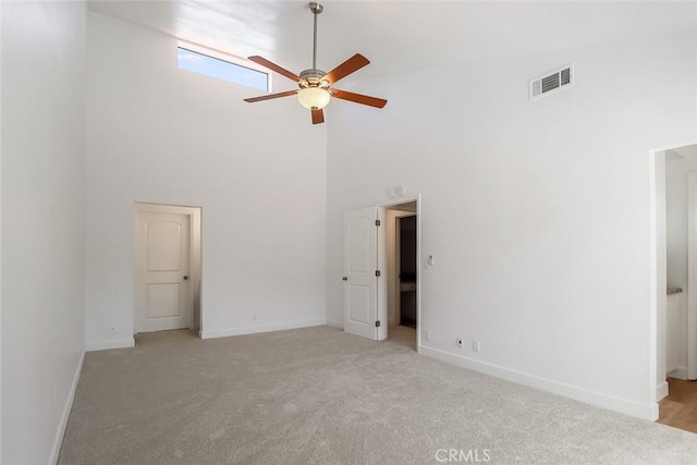 carpeted spare room featuring high vaulted ceiling and ceiling fan