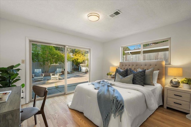 bedroom featuring a textured ceiling, access to exterior, and light wood-type flooring